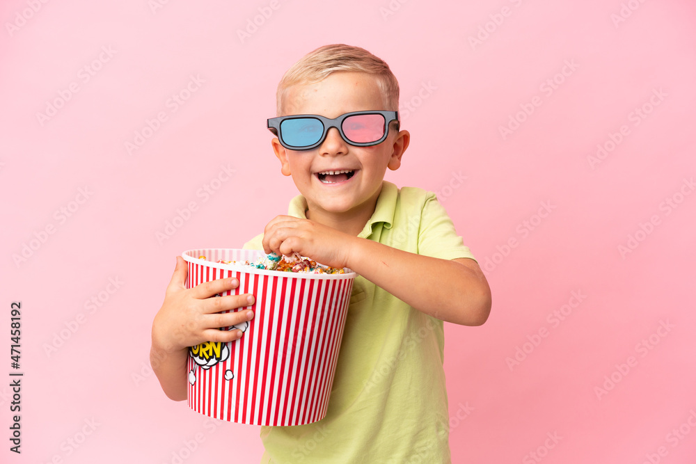 Little Russian boy eating popcorns in a big bowl over isolated background Little Russian boy eating popcorns in a big bowl over isolated background