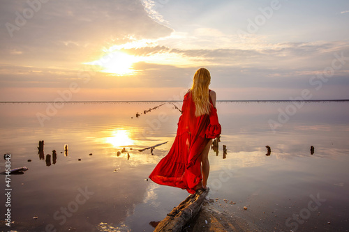 girl in a red long dress posing at sunset on the famous pink salt lake photo