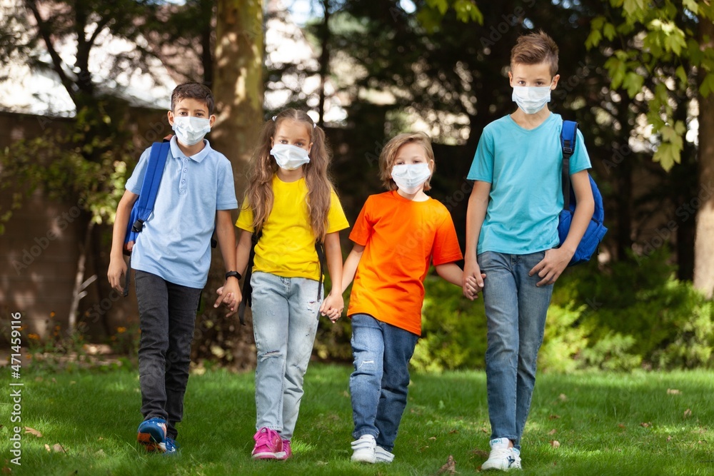 Group of schoolchildren in masks walking together on the park Group of schoolchildren in masks walking together on the park