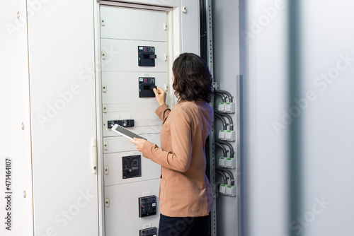 back view of technician with digital tablet operating switchboard in data center