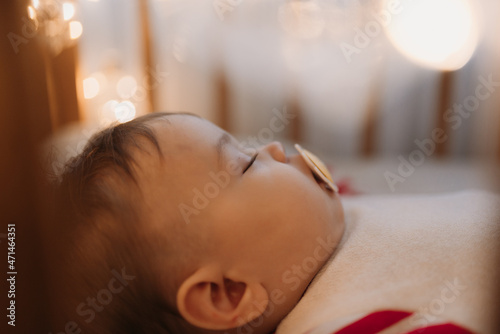 a little boy sleeps to the crib with a yellow pacifier red striped suit