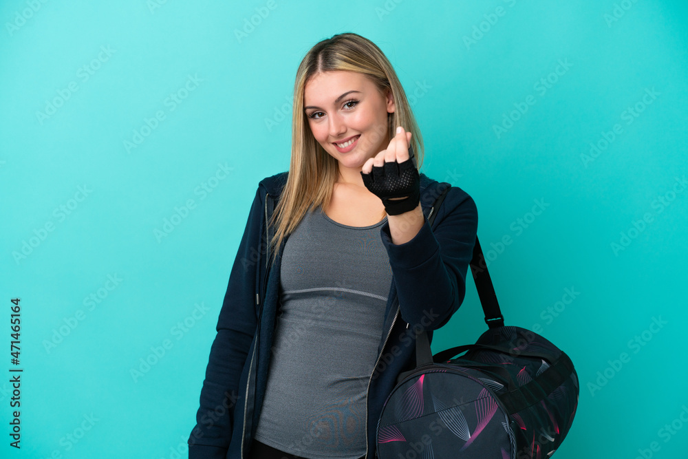Young sport woman with sport bag isolated on blue background making money gesture Young sport woman with sport bag isolated on blue background making money gesture