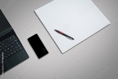 laptop on a desk with smartphone,  white paper and pen