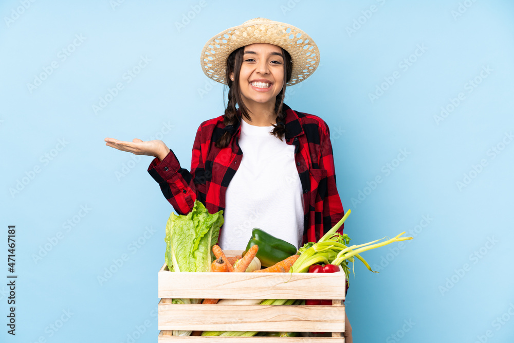Young farmer Woman holding fresh vegetables in a wooden basket holding copyspace imaginary on the palm to insert an ad
