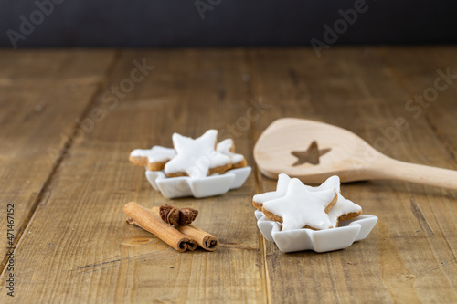 christmas cookies (cinnamon stars) in a little bowl, focus on foreground, wooden cooking spoon in the background 