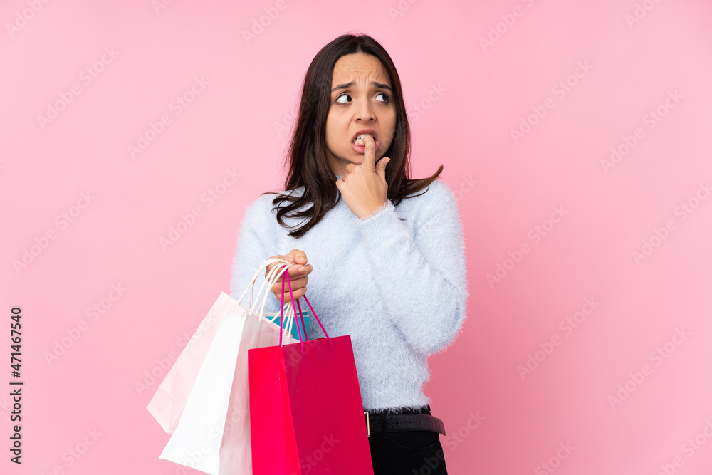Young woman with shopping bag over isolated pink background nervous and scared