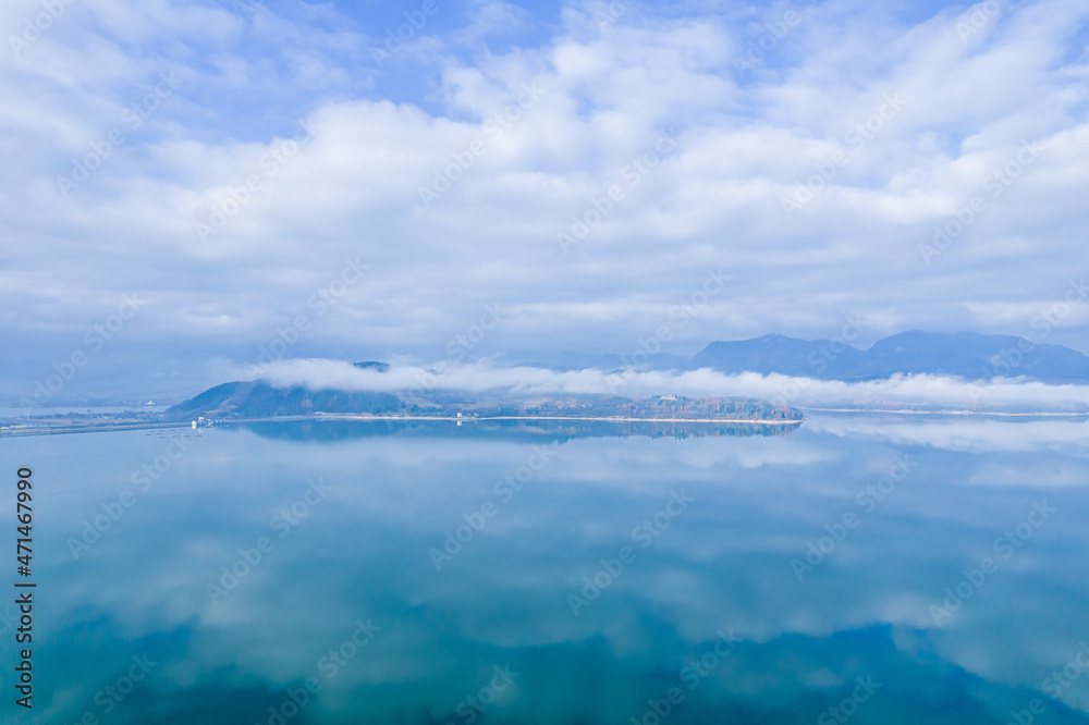 Heavy fog in the mountains. Reflection of blue sky and white clouds on the lake.