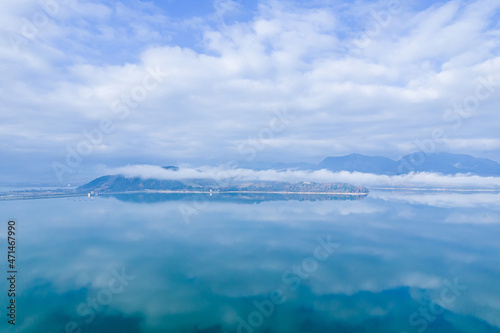Heavy fog in the mountains. Reflection of blue sky and white clouds on the lake.