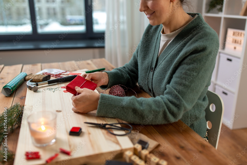 winter holidays and hobby concept - close up of woman with box and rope packing christmas gift or making advent calendar at home