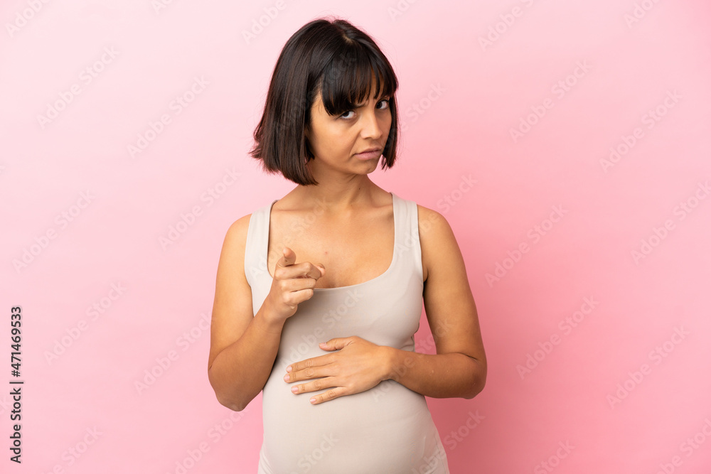 Young pregnant woman over isolated pink background frustrated and pointing to the front Young pregnant woman over isolated pink background frustrated and pointing to the front