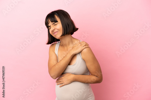 Young pregnant woman over isolated pink background suffering from pain in shoulder for having made an effort