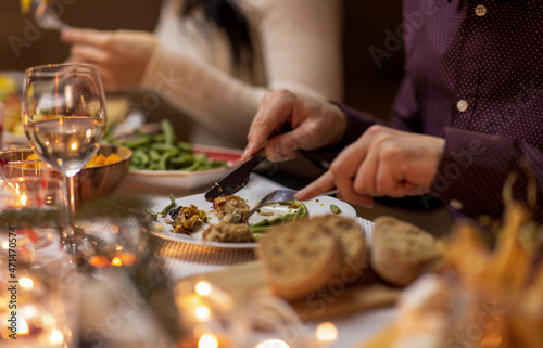 food, holidays and celebration concept - close up of man having christmas dinner and eating meat at home