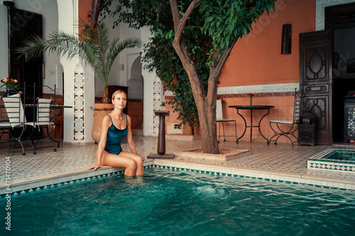 Retreat and vacation. Beautiful young woman relaxing in spa private swimming pool in beautiful moroccan backyard. © luengo_ua