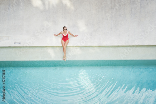 Enjoying suntan and vacation. Top view of pretty young woman in red swimsuit lying near swimming pool. © luengo_ua
