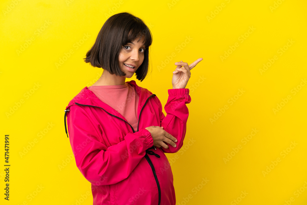 Young pregnant woman over isolated yellow background pointing finger to the side Young pregnant woman over isolated yellow background pointing finger to the side