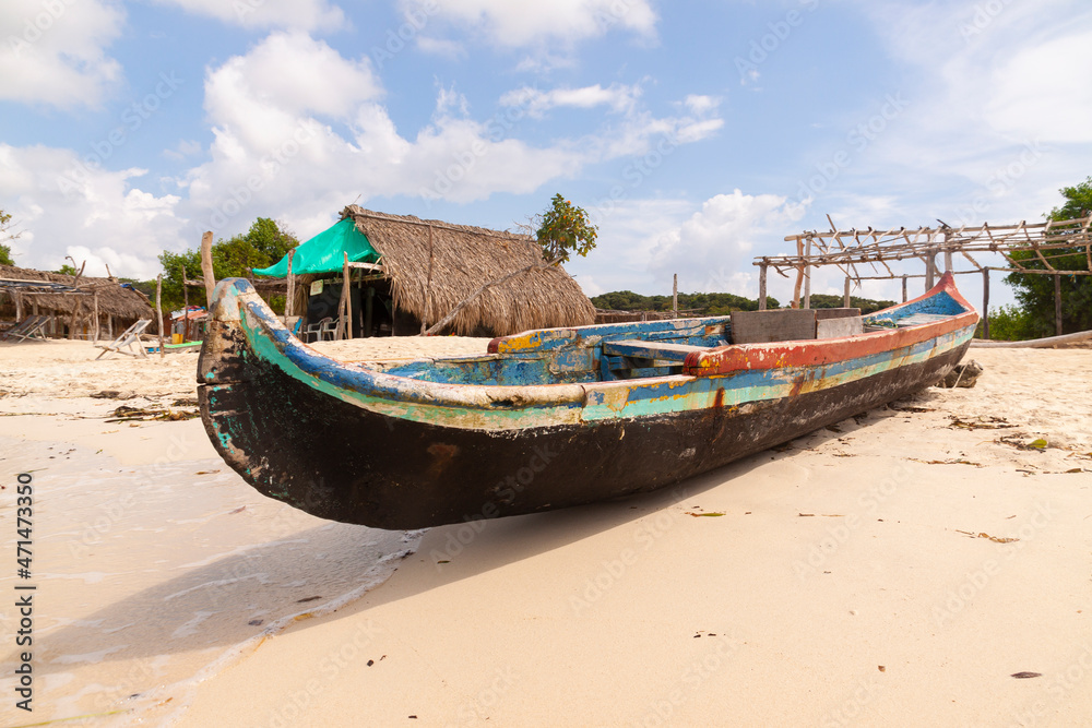 An old fishing boat, built with wood and painted in colors, barada on the beach of Isla Baru, in the Colombian Caribbean