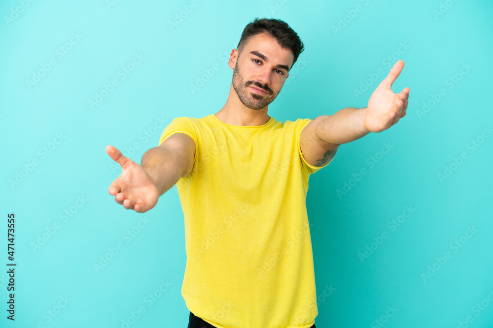 Young caucasian man isolated on blue background presenting and inviting to come with hand Young caucasian man isolated on blue background presenting and inviting to come with hand