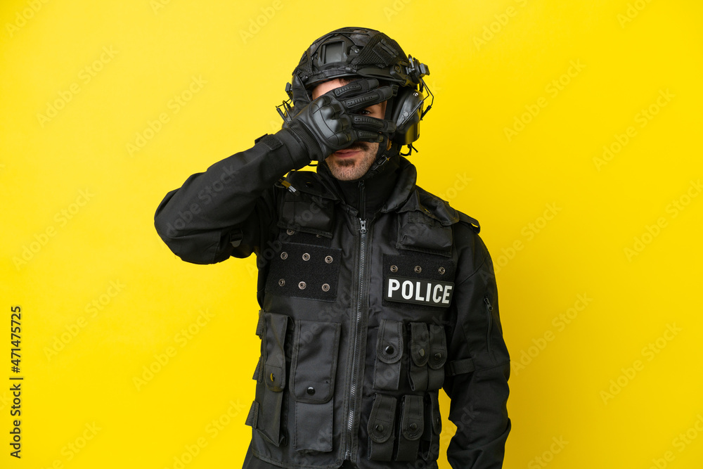SWAT caucasian man isolated on yellow background covering eyes by hands and smiling SWAT caucasian man isolated on yellow background covering eyes by hands and smiling