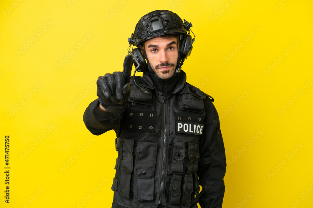 SWAT caucasian man isolated on yellow background showing and lifting a finger SWAT caucasian man isolated on yellow background showing and lifting a finger