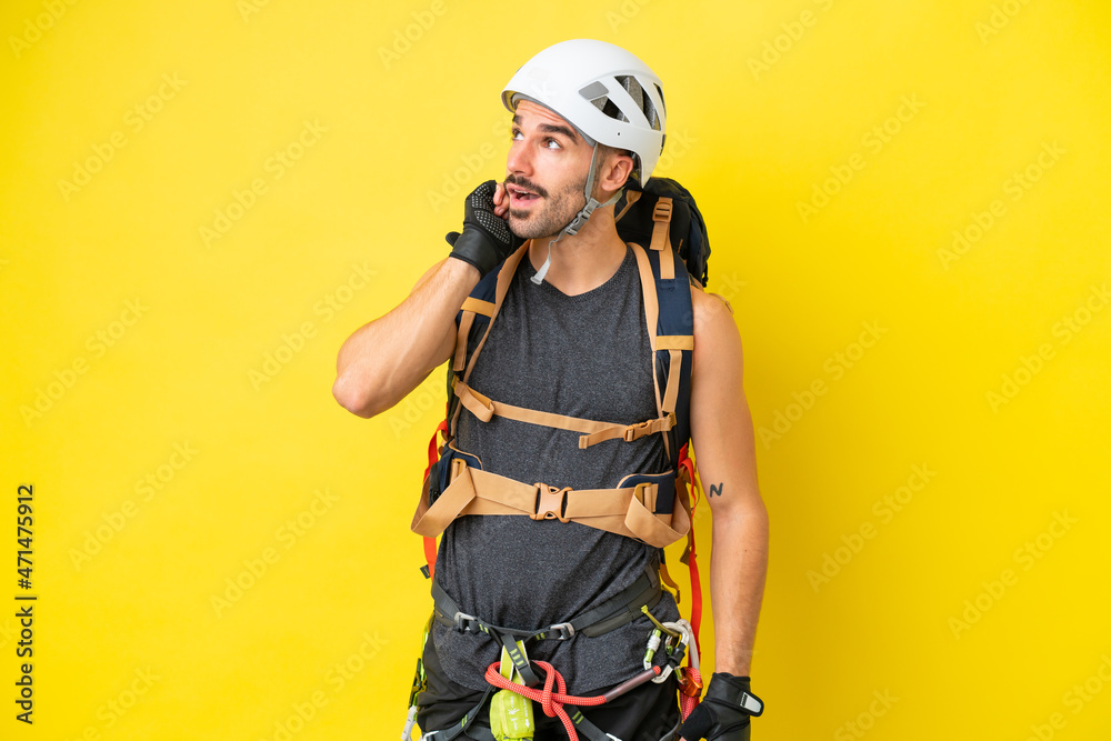 Young caucasian rock climber man isolated on yellow background thinking an idea Young caucasian rock climber man isolated on yellow background thinking an idea
