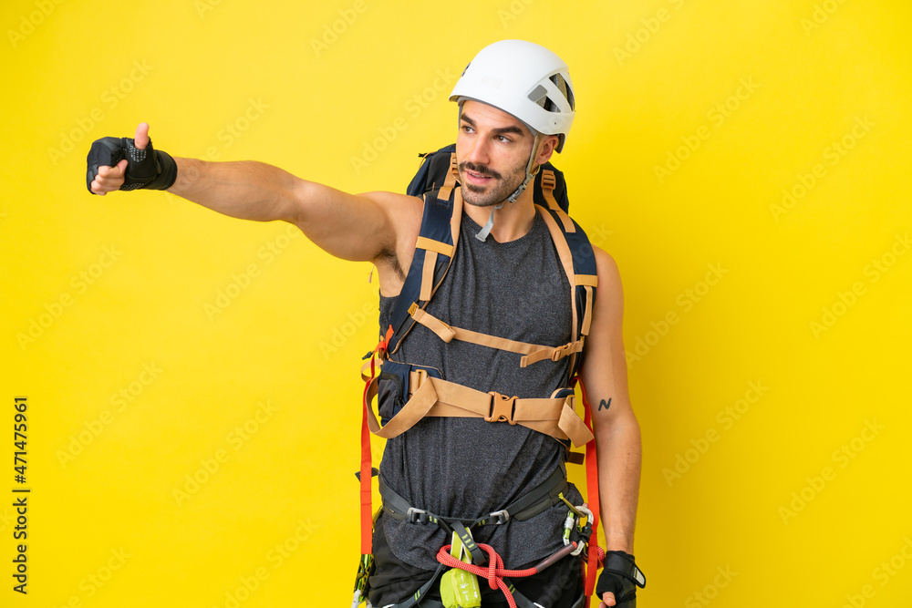 Young caucasian rock climber man isolated on yellow background giving a thumbs up gesture