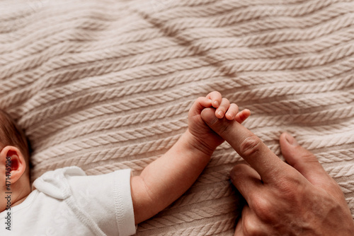 the legs of a newborn baby in dad's hands
