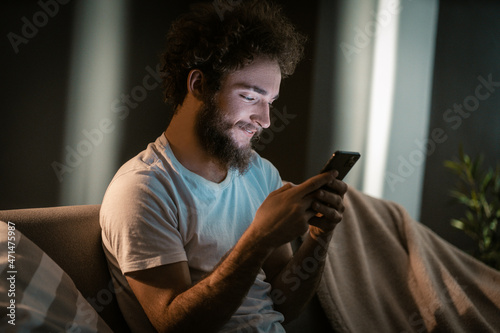 Foto Nice Guy Texting to his Girlfriend by his Smartphone in the evening