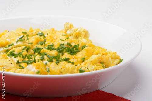 scrambled breakfast eggs on a white plate with red and white background