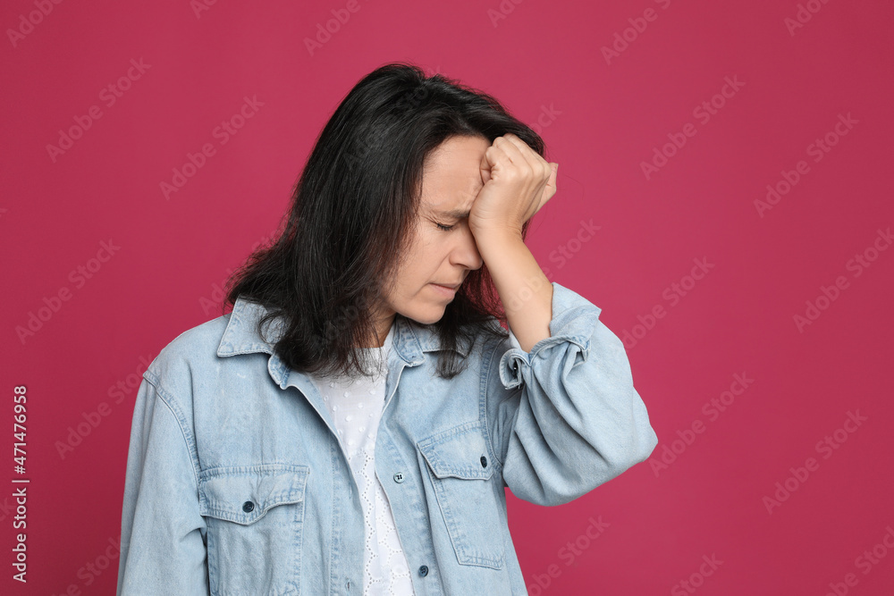 Mature woman suffering from headache on pink background Mature woman suffering from headache on pink background