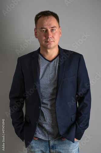 Portrait of a 30s man in a jacket and T-shirt on a gray background © Larisa