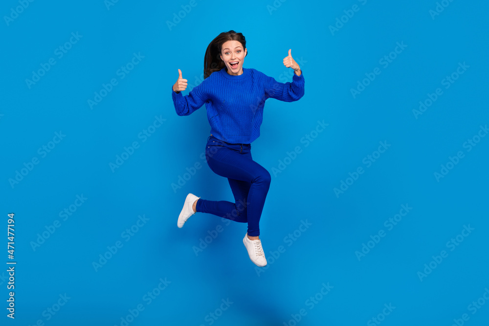 Fototapeta premium Full length body size view of attractive cheerful glad girl jumping running showing thumbup isolated on bright blue color background