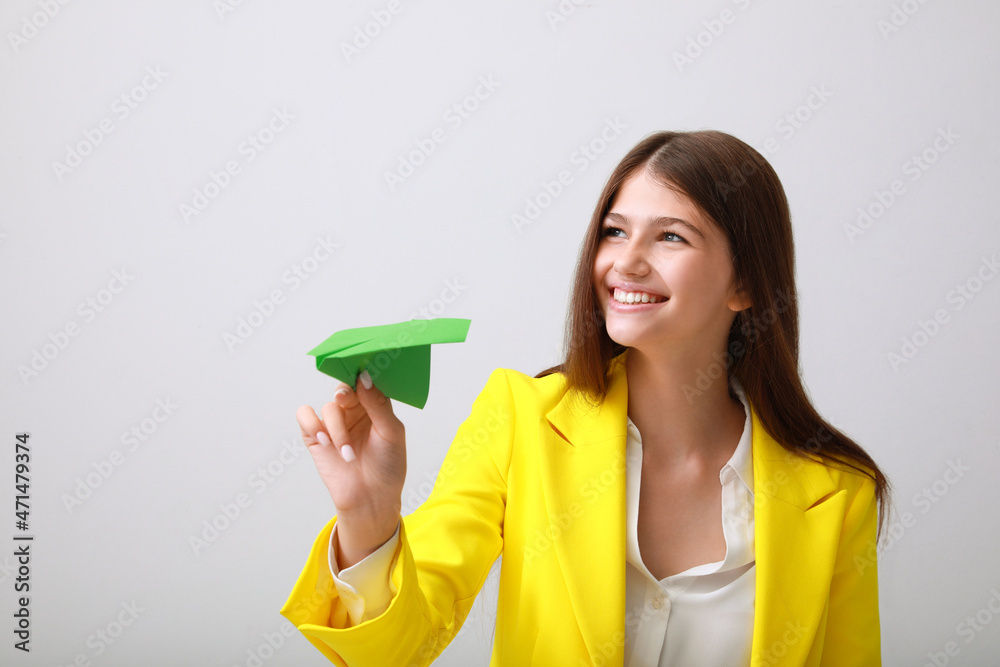 Beautiful teenage girl with paper plane on grey background Beautiful teenage girl with paper plane on grey background