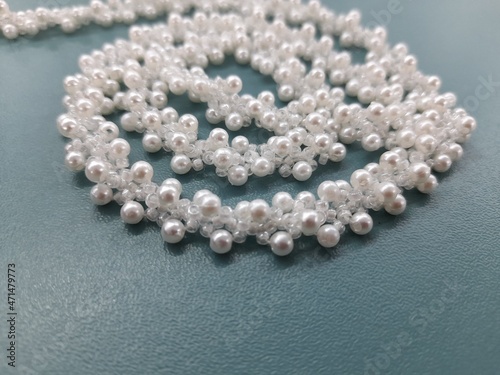 Wicker belt made of white pearls. The belt is lined with a spiral on a turquoise surface.