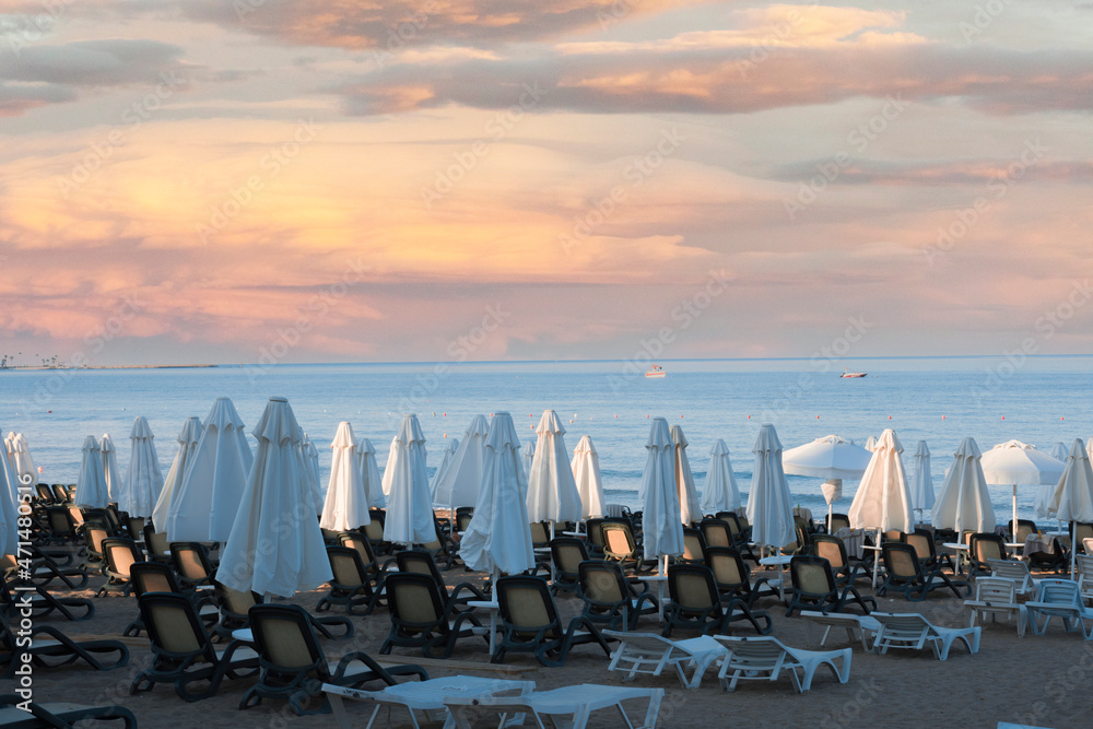 Obraz premium Beach views, Sun loungers, umbrellas, flags and small wavy coastline in Antalya Side. Selective Focus.