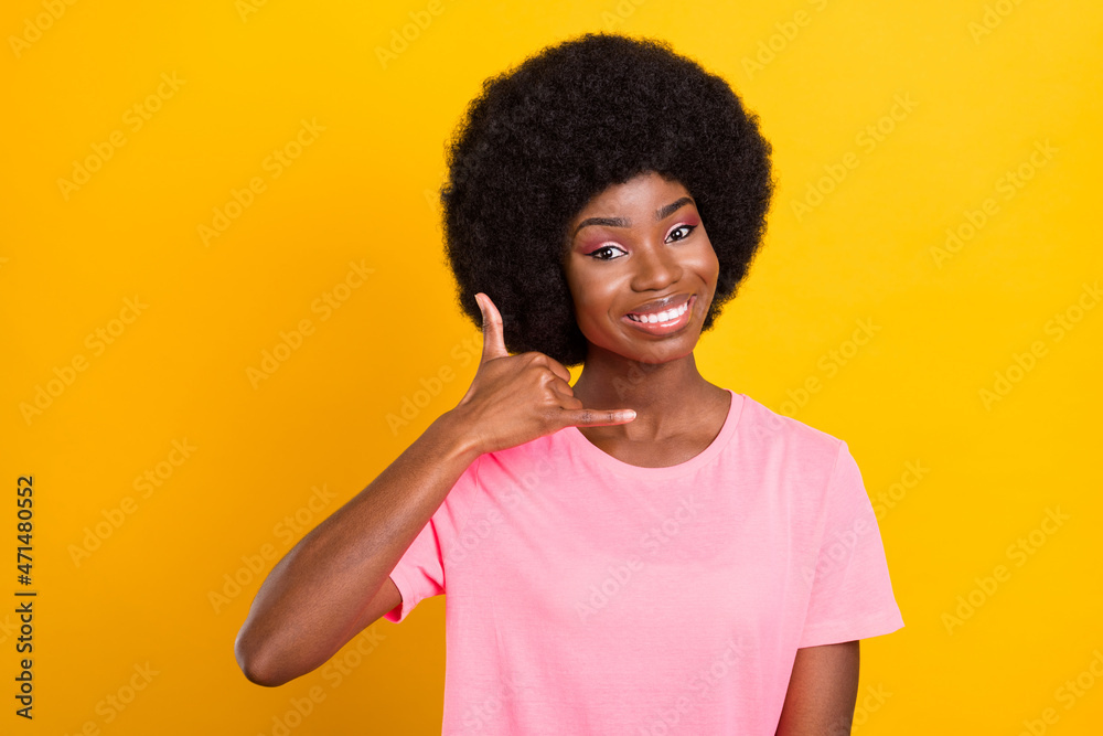 Photo of young cheerful black girl happy positive smile show fingers call talk sign isolated over yellow color background Photo of young cheerful black girl happy positive smile show fingers call talk sign isolated over yellow color background