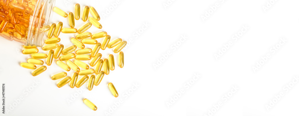 Obraz premium Fish oil in gelatin capsules isolate. Omega vitamins in golden colored pills on a blank white banner background. Medicine, pharmacy, drugs and multivitamins oils concept