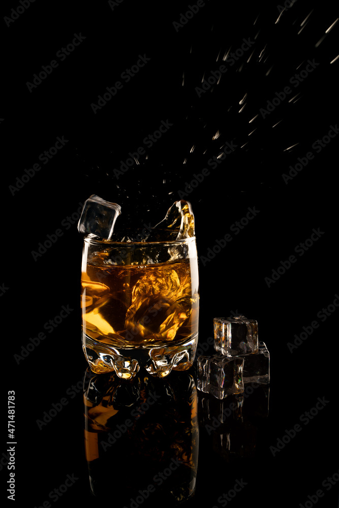 a glass of whiskey with ice and splashes on a black background a glass of whiskey with ice and splashes on a black background