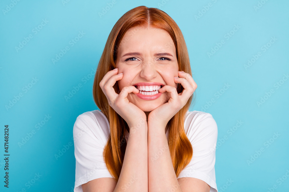 Photo of unsatisfied orange hair lady hands on face biting finger nail look camera isolated on blue color background Photo of unsatisfied orange hair lady hands on face biting finger nail look camera isolated on blue color background