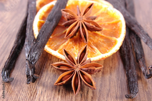 Star anise, fragrant vanilla and dried orange on wooden plank