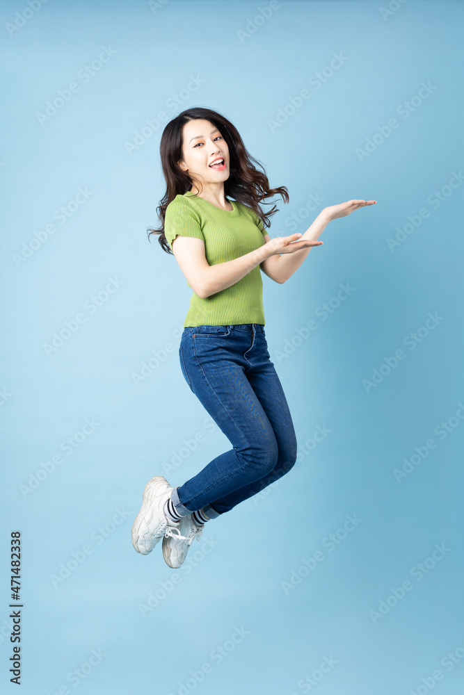 Portrait of beautiful young asian girl jumping up, isolated on blue background