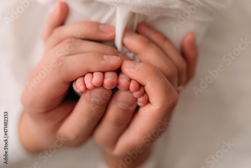 dad holds the legs of a newborn baby, heels, fingers, newborn