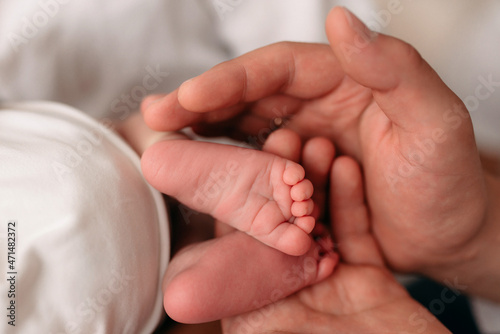 dad holds the legs of a newborn baby, heels, fingers, newborn