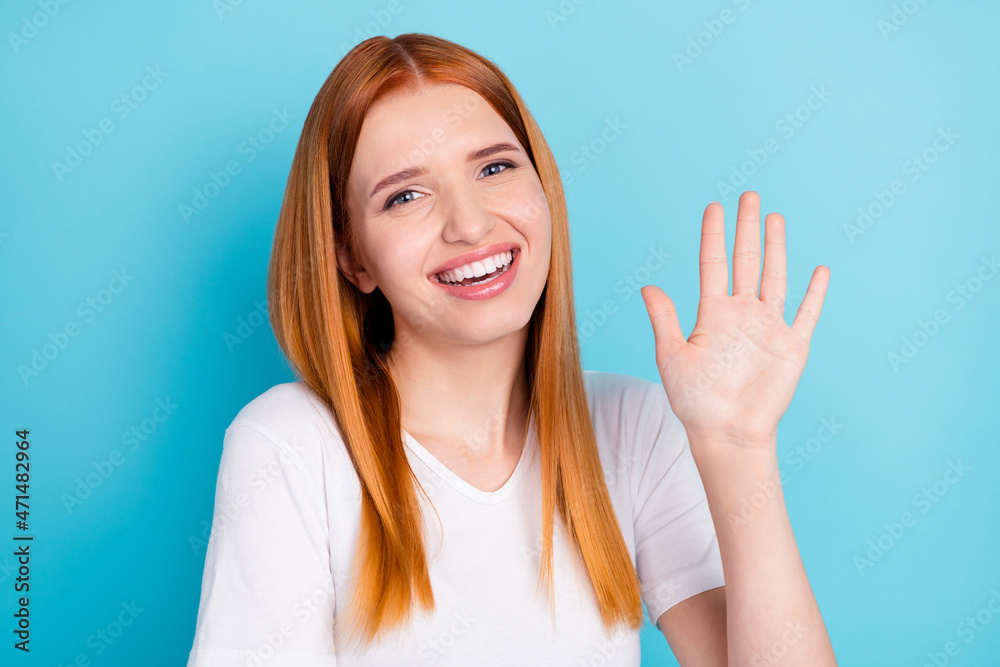Photo of satisfied orange hair girl beaming smile arm palm wave look camera isolated on blue color background Photo of satisfied orange hair girl beaming smile arm palm wave look camera isolated on blue color background