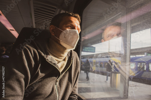Man in protective mask N-95 in train. Tourist looking in window inside of railway wagon. Travel in quarantine. New lifestyle. Journey during epidemic time. Railway transportation. Hygiene while travel