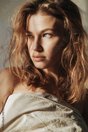 Принти на полотні Fashion portrait of young blondish girl hiding behind a blanket with an interesting light on her face