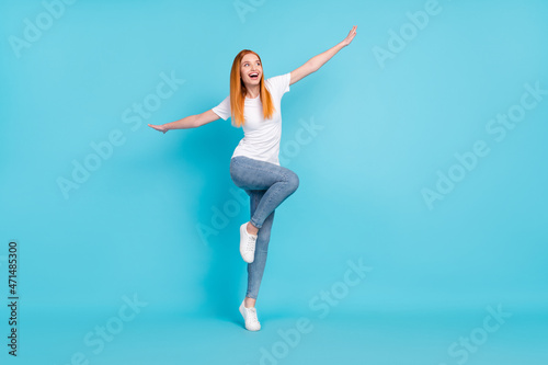 Full length photo of young girl happy positive smile playful hands wings look empty space isolated over blue color background