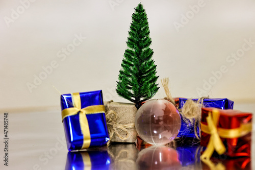 Merry Christmas, Happy New Year and Boxing day concept. Present boxes, world gloge crystal glass, pine tree and house models on light brown background. photo
