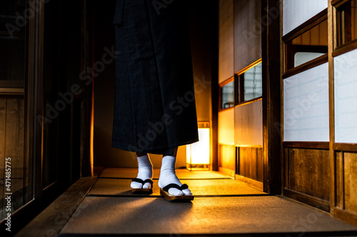 Traditional Japan Japanese house or ryokan with man in kimono walking closeup of legs with geta tabi shoes and white socks by shoji sliding paper doors and tatami mat photo