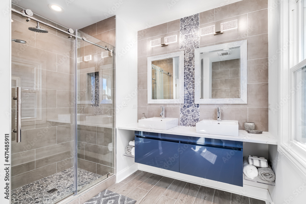 A modern bathroom with a blue cabinet, tile and stone back splash, and  marble tiling the floor / shower. Stock Photo