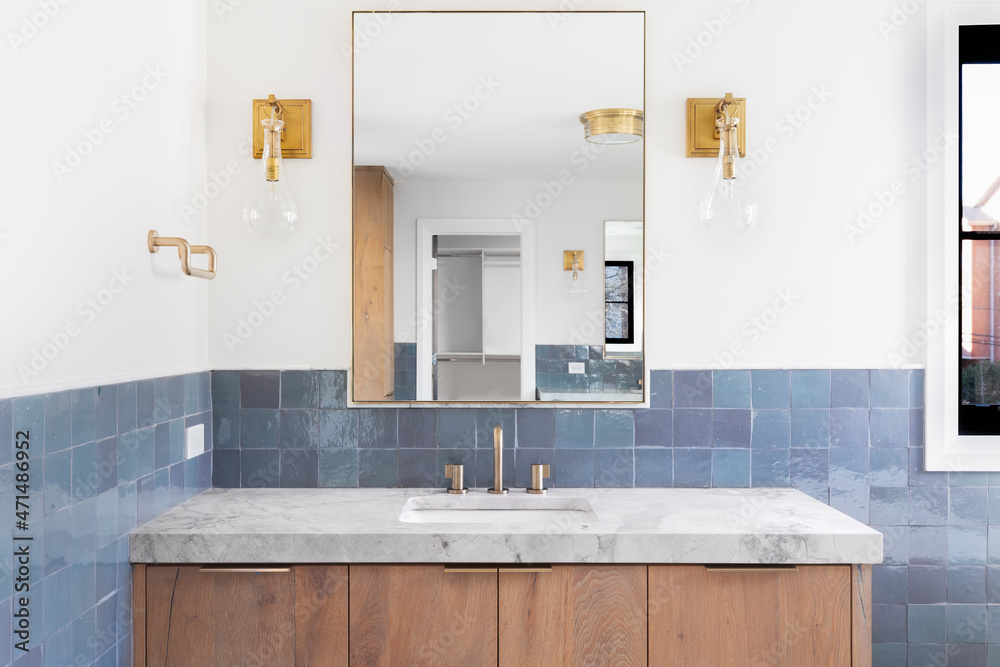 A luxury home's renovated bathroom with blue tiles, a light wood vanity